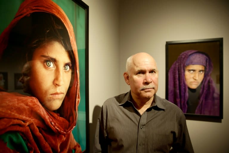 US photographer Steve McCurry poses next to his photos of the "Afghan Girl" named Sharbat Gula at the opening of the "Overwhelmed by Life" exhibition of his work at the Museum for Art and Trade in Hamburg, northern Germany on June 27, 2013