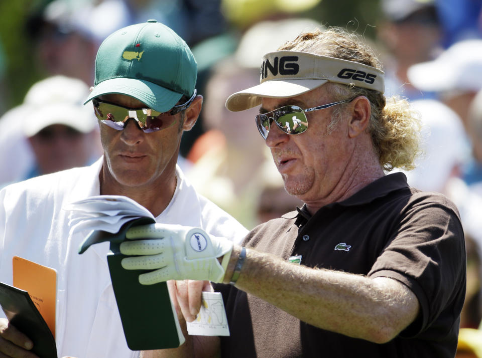 Miguel Angel Jimenez, of Spain, checks his notebook with caddie Clifford Botha before teeing off on the sixth hole during the third round of the Masters golf tournament Saturday, April 12, 2014, in Augusta, Ga. (AP Photo/Darron Cummings)