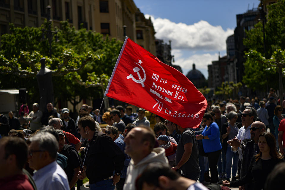 A person waves a flag with the traditional communist symbol during a May Day rally in Pamplona, northern Spain, Monday, May 1, 2023. (AP Photo/Alvaro Barrientos)