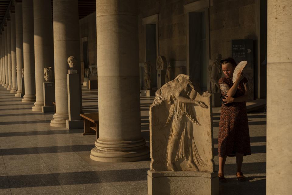 A tourist uses a fan inside Stoa of Attalos, at ancient Agora, in Athens, on Thursday, July 20, 2023. (AP Photo/Petros Giannakouris)