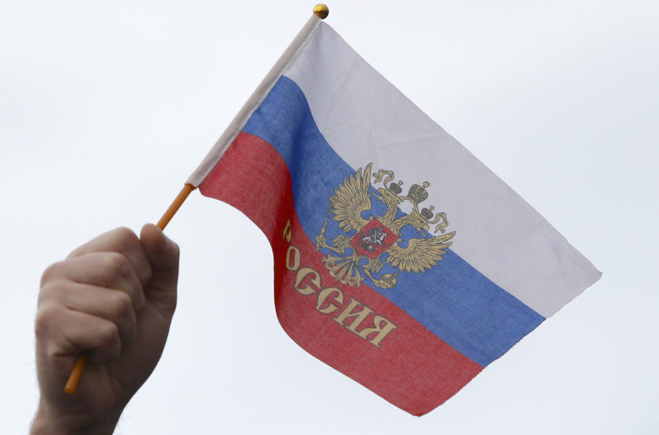 In this photo taken Wednesday, March 5, 2014, a local resident holds Russian flag during a rally at a central square in Simferopol, Ukraine. Ukraine is facing a potentially crippling geographic and cultural divide, a growing gulf between supporters of Russia who dominate the east and south of the country, and western Ukrainians who yearn for closer ties to Western Europe. One side of that divide is even starker in Crimea, a Black Sea peninsula. For much of the past 200 years, Crimea was under Russian and Soviet control, and today most Crimeans see themselves as only nominally Ukrainian and Russian is, by far, the dominant language (AP Photo/Sergei Grits)