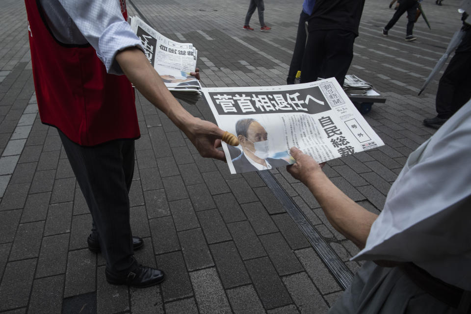 A staffer for a Japanese newspaper hands out a copy of the extra issue for Japanese Prime Minister Yoshihide Suga's announcement of not running for leadership of the governing party later this month, near a train station in Tokyo, Friday, Sept. 3, 2021. Suga said Friday he won't run for leadership of the governing party at the end of this month, paving the way for a new Japanese leader after just a year in office. The headline reads: "Prime Minister Suga to resign." (AP Photo/Hiro Komae)