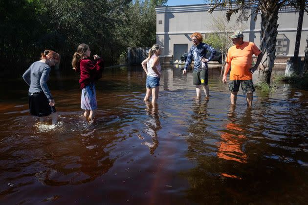 A family gathers in a flooded parking lot in New Smyrna Beach, Florida, on Sept. 30. (Photo: JIM WATSON via Getty Images)