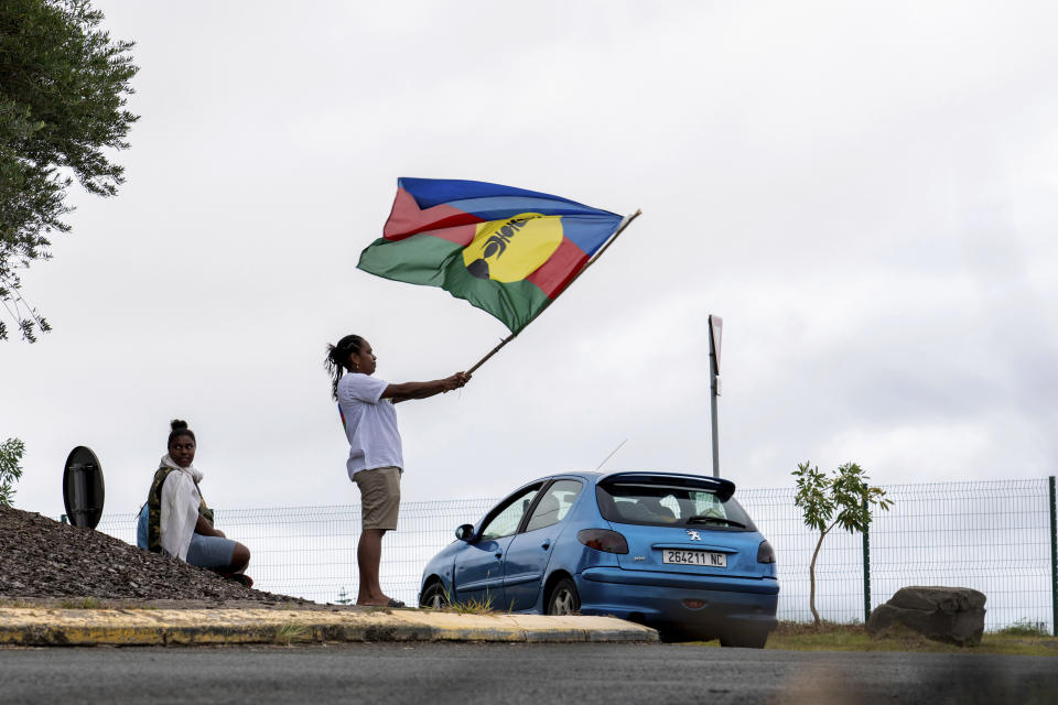 A woman waves a Kanak and Socialist National Liberation Front (FLNKS) flag in Noumea, New Caledonia, Wednesday May 15, 2024. France has imposed a state of emergency in the French Pacific territory of New Caledonia. The measures imposed on Wednesday for at least 12 days boost security forces' powers to quell deadly unrest that has left four people dead, erupting after protests over voting reforms. (AP Photo/Nicolas Job)