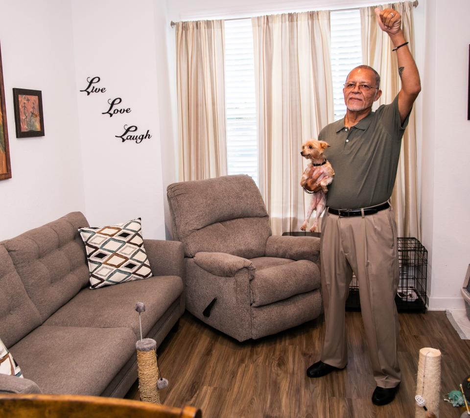 Oak Valley resident Nelson Satones, holding his dog Milo, waves to people and welcomes them in to his apartment on Thursday at Oak Valley, a new affordable housing community for seniors.