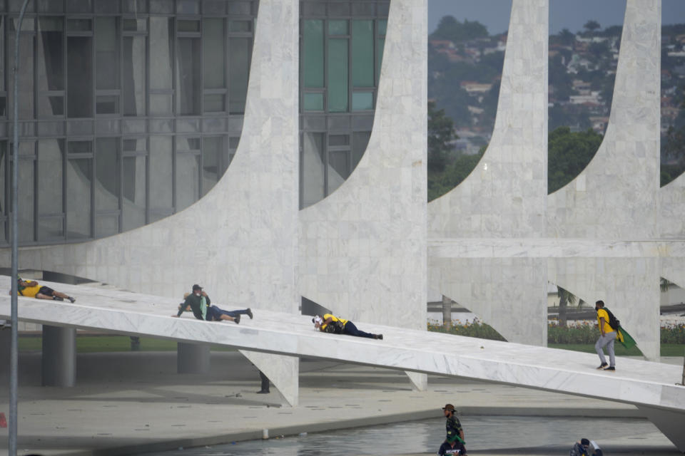 Protesters, supporters of Brazil's former President Jair Bolsonaro, lay on the ramp of Planalto Palace during clashes with police as protesters storm the official workplace of the president in Brasilia, Brazil, Sunday, Jan. 8, 2023. (AP Photo/Eraldo Peres)