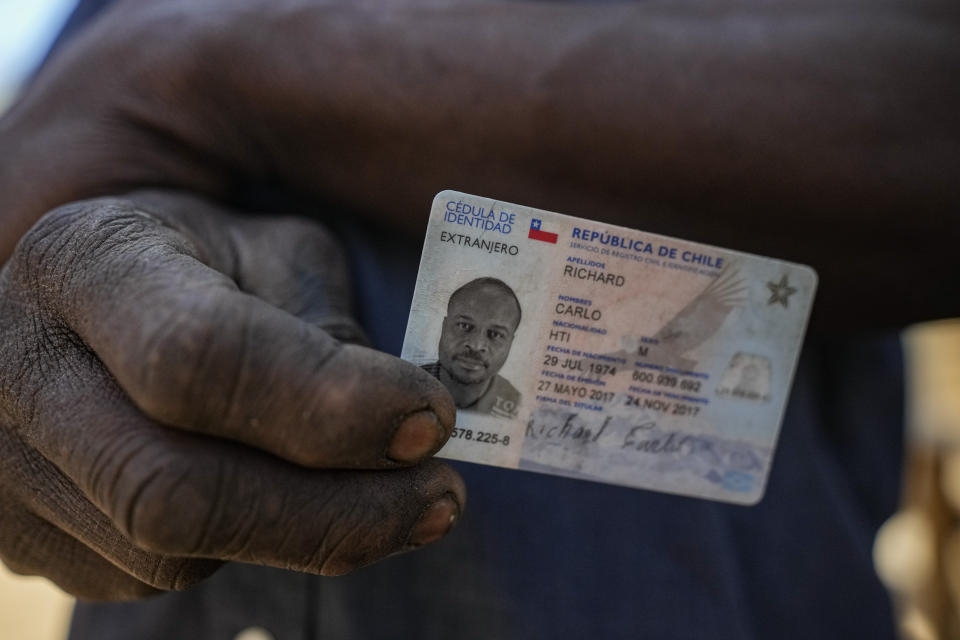 Haitian migrant Carlo Richard shows his expired Chilean identity card, which was good for six months then rejected for renewal, at home in a camp named "Bosque Hermoso," or Beautiful Forest in Lampa, Chile, Friday, Oct. 1, 2021. The auto mechanic who has resided in Chile since 2017 is one of thousands who live in fear of being expelled. (AP Photo/Esteban Felix)