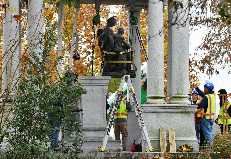 The bronze statue of a woman reading to two children is slid off its base as it is removed from the "Women of the Southland" monument Wednesday morning in Springfield Park. Jacksonville's Mayor Donna Deegan made removing the monument a major part of her successful campaign for mayor.