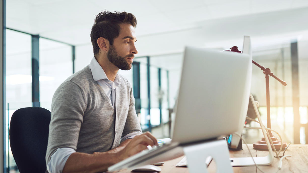 Shot of a designer working on his computer and laptop in a modern office.