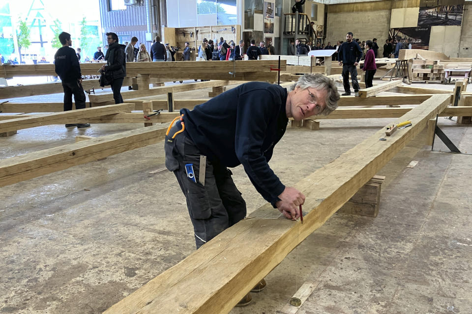 Peter Henrikson, 61, a timber framer from Minnesota, measures a beam, part of the new roof of the Notre Dame cathedral de Paris, Thursday, May, 25, 2023., near Angers, western France. Carpenters building a new timber frame for the fire-ravaged roof of Paris' Notre Dame Cathedral are using the same tools and techniques as their medieval predecessors. For them, working with hand-axes to fashion oak beams has been like stepping back in time. (AP Photo/Jeffrey Schaeffer)