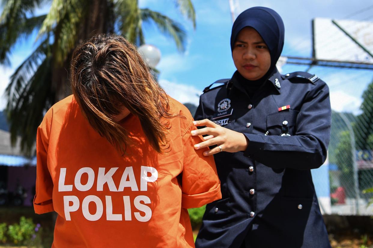 British national Samantha Jones (L) is escorted by a police officer as she arrives at a court in Langkawi on October 30, 2018. - Jones, 51, was detained after her husband John William Jones, 62, was found with a stab wound to his chest on the floor of his house on Langkawi. (Photo by Alif BAKRI / AFP)        (Photo credit should read ALIF BAKRI/AFP via Getty Images)