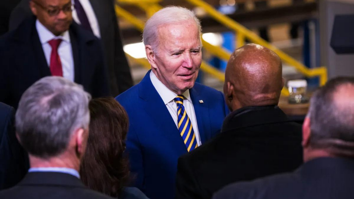 A white man talks to a Black man as a crowd of people surrounds them. 