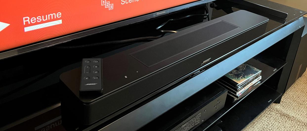  Bose Soundbar 600 on TV stand with red screen in background. 