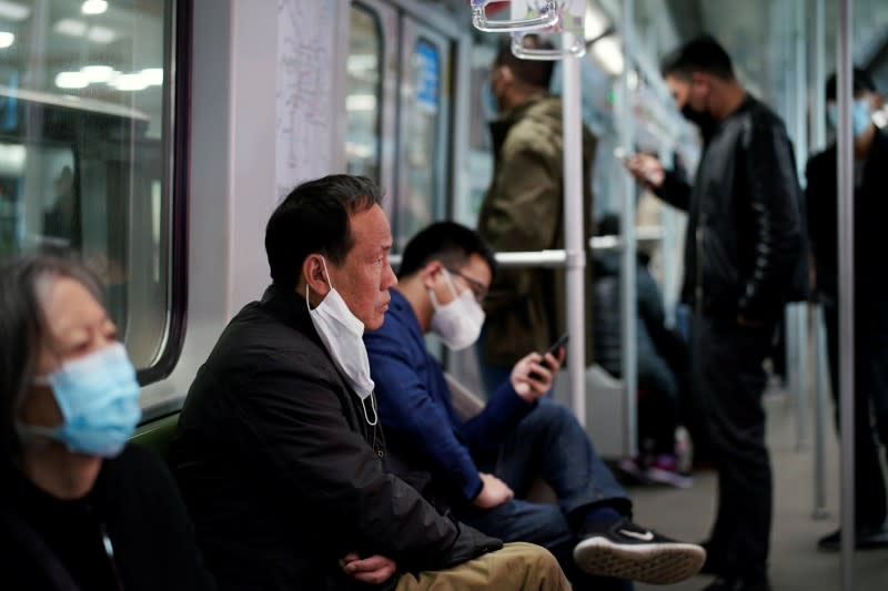 Passengers with face masks ride a subway after the city's emergency alert level for coronavirus disease (COVID-19) was downgraded, in Shanghai,