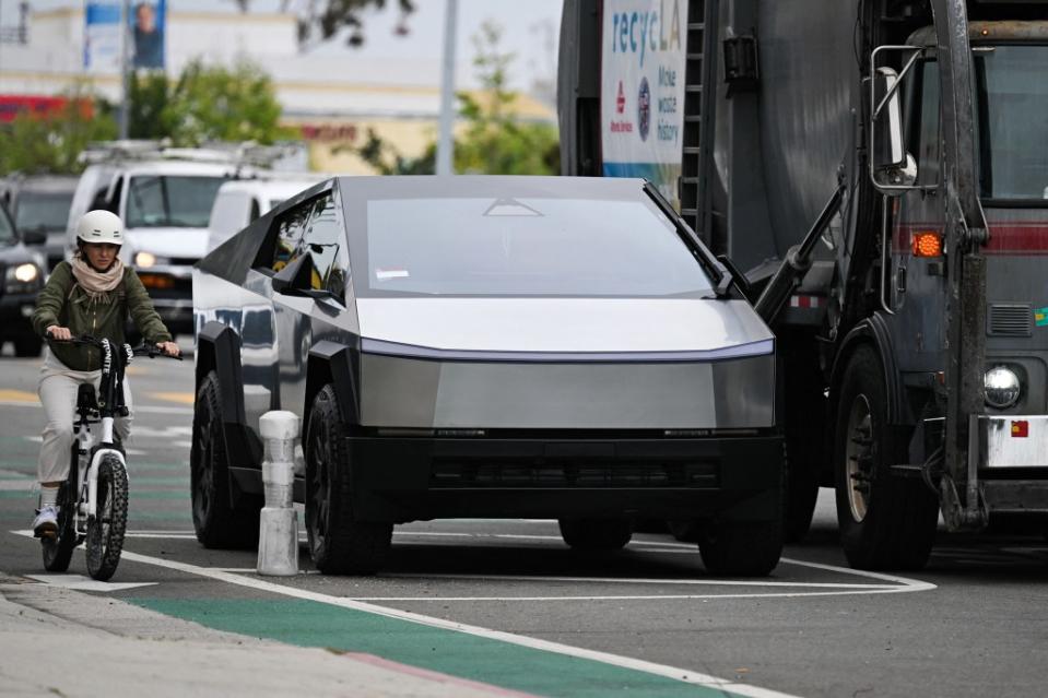 A cyclist rides past a Tesla Cybertruck electric vehicle parked next to a garbage truck in Los Angeles, California, on May 15, 2024. Stock markets struck record highs Wednesday after official data showed US inflation cooled slightly in April, raising hopes that the Federal Reserve will cut interest rates in the coming months. (Photo by Patrick T. Fallon / AFP) (Photo by PATRICK T. FALLON/AFP via Getty Images)