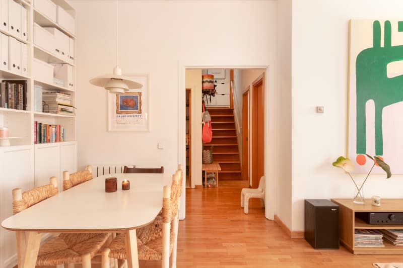 White dining room with floor-to-ceiling bookshelves and view of wood stairway in the background