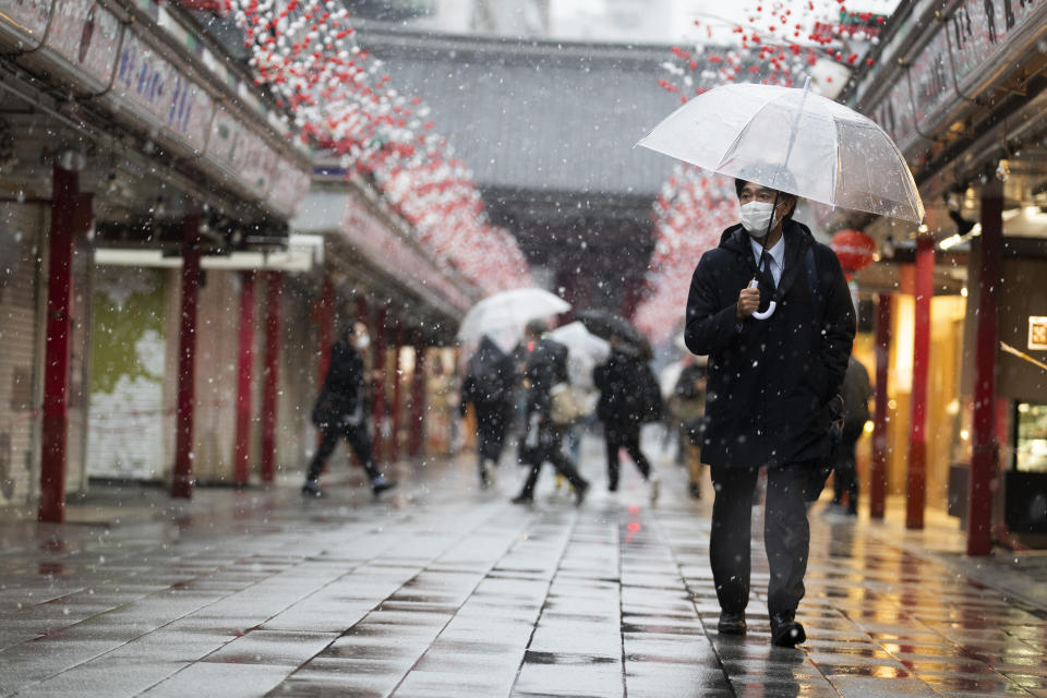 A man wearing a face mask walks through the Sensoji temple in the snow in Tokyo on Thursday, Jan. 28, 2021. (AP Photo/Hiro Komae)
