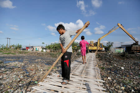 A boy uses a bamboo stick to clean a river covered by rubbish in Bekasi, West Java province, Indonesia, January 7, 2019. REUTERS/Willy Kurniawan/Files