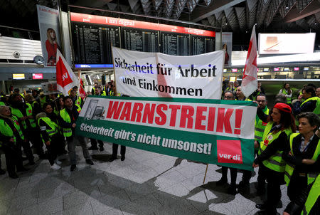 Union members holding placards reading "Safety for job and income" (top) and "warning strike - security isn't free of charge" during a strike over higher wages at Germany's largest airport in Frankfurt, Germany, January 15, 2019. REUTERS/Kai Pfaffenbach