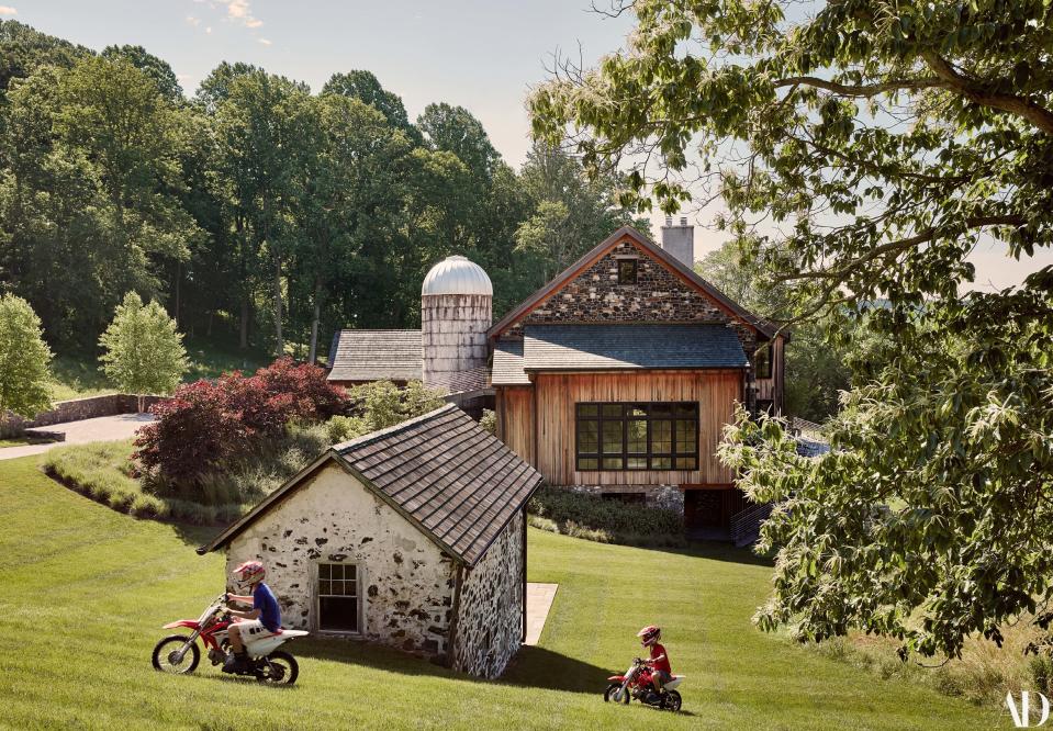 Tomás and Roberto Buccini bike past the original well house at the family’s home, a renovated 1860s barn, in Chadds Ford, Pennsylvania.