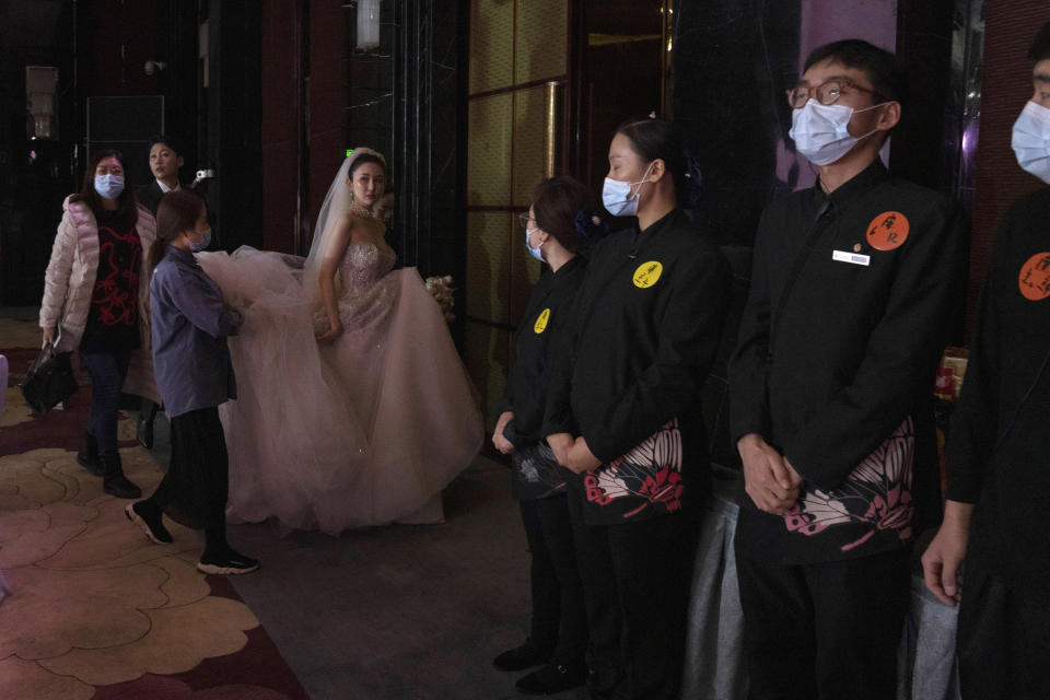 Bride Chen Yaxuan walks by staff wearing masks during a wedding banquet in Beijing on Saturday, Dec. 12, 2020. Lovebirds in China are embracing a sense of normalcy as the COVID pandemic appears to be under control in the country where it was first detected. (AP Photo/Ng Han Guan)