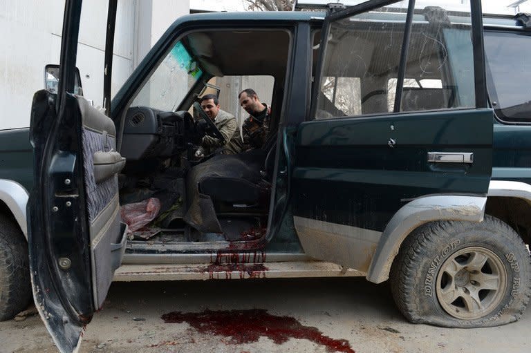 Afghan security officials inspect a suicide bomber's car in Kabul on February 24, 2013. The attacker was armed with a suicide vest and his SUV was full of explosives, but police opened fire when he tried to penetrate deeper into the capital's diplomatic enclave of Wazir Akbar Khan, officials said