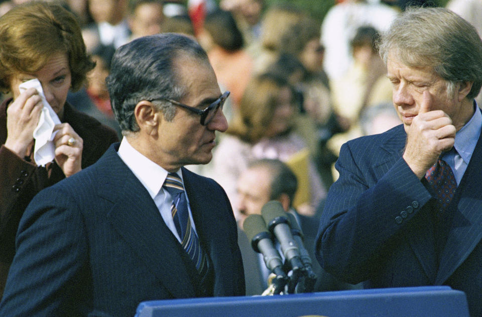 FILE - In this Nov. 15, 1977 file photo, then-first lady Rosalyn Carter, left, Shah Mohammad Reza Pahlavi, center, and then U.S. President Jimmy Carter, right, react to wafting tear gas as pro- and counter-shah demonstrators clash with police outside of the White House during a ceremony. Dozens would be injured in the violence. Forty years ago, Iran's ruling shah left his nation for the last time and an Islamic Revolution overthrew the vestiges of his caretaker government. The effects of the 1979 revolution, including the takeover of the U.S. Embassy in Tehran and ensuing hostage crisis, reverberate through decades of tense relations between Iran and America. (AP Photo, File)