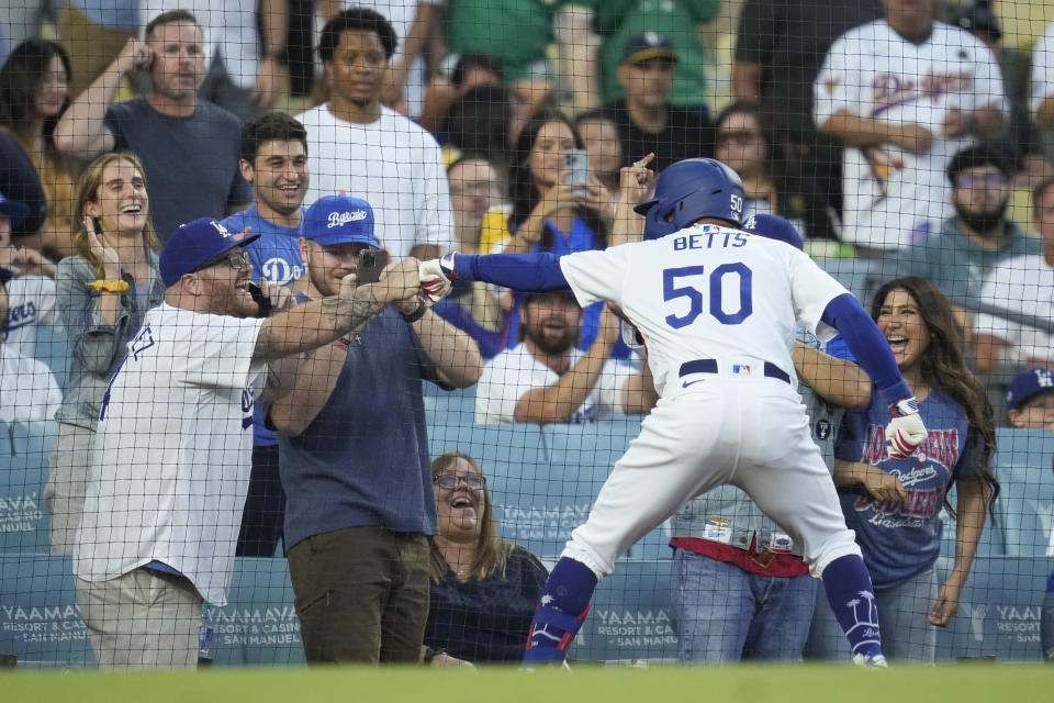 Los Angeles Dodgers' Mookie Betts fist bumps a fan after hitting a home run during the second inning of a baseball game against the Oakland Athletics in Los Angeles, Wednesday, Aug. 2, 2023. (AP Photo/Ashley Landis)