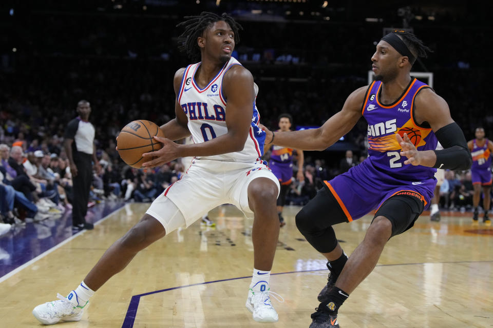 Philadelphia 76ers guard Tyrese Maxey (0) shields the ball from Phoenix Suns forward Josh Okogie during the second half of an NBA basketball game Saturday, March 25, 2023, in Phoenix. The Suns won 125-105. (AP Photo/Rick Scuteri)