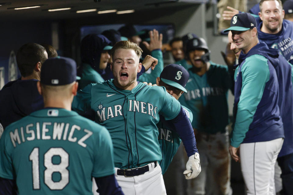 Seattle Mariners' Jarred Kelenic celebrates with relief pitcher Anthony Misiewicz and other teammates in the dugout after hitting two-run home run during the eighth inning of a baseball game against the Tampa Bay Rays, Friday, May 6, 2022, in Seattle. (AP Photo/Jason Redmond)