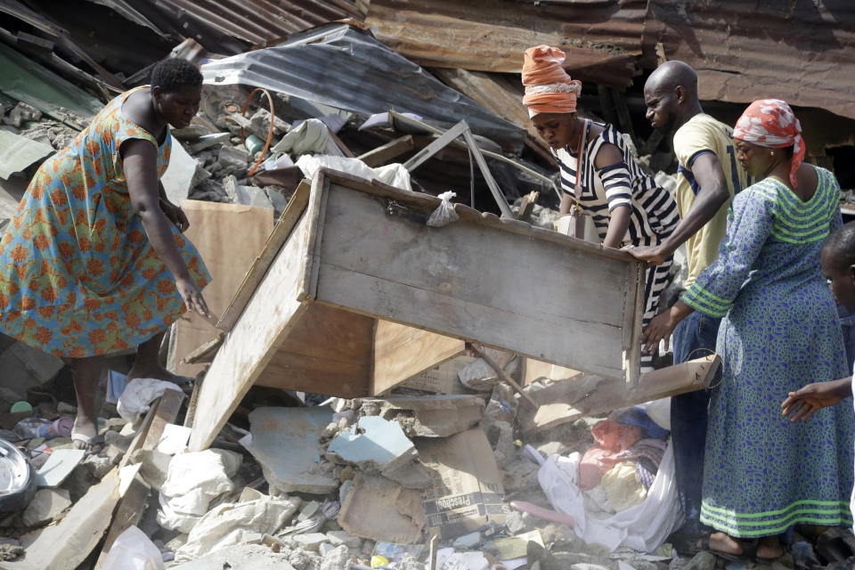 Local people attend the scene after a building collapsed in Lagos, Nigeria, Thursday March 14, 2019. Search and rescue work continues in Nigeria a day after a building containing a school collapsed with scores of children said to be inside. A National Emergency Management Agency spokesman late Wednesday said 37 people had been pulled out alive, with eight bodies recovered from the ruins. (AP Photo/Sunday Alamba)