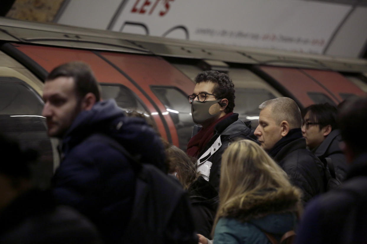 A man wearing a face mask waits to board an underground train on the Central Line at Bank station in London, Wednesday, March 4, 2020. British authorities laid out plans Tuesday to confront a COVID-19 epidemic, saying that the new coronavirus could spread within weeks from a few dozen confirmed cases to millions of infections, with thousands of people in the U.K. at risk of death. (AP Photo/Matt Dunham)