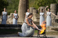 Greek actress Xanthi Georgiou, playing the role of the High Priestess, lights the torch during the lighting of the Olympic flame at Ancient Olympia site, birthplace of the ancient Olympics in southwestern Greece, Monday, Oct. 18, 2021. The flame will be transported by torch relay to Beijing, China, which will host the Feb. 4-20, 2022 Winter Olympics. (AP Photo/Thanassis Stavrakis)