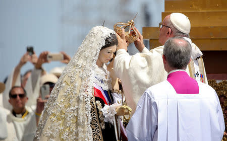 Pope Francis puts a crown on a statue as he celebrates a Mass at Lobito beach in Iquique, Chile, January 18, 2018. REUTERS/Alessandro Bianchi