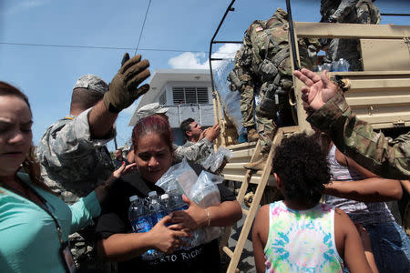 FILE PHOTO: A woman carries bottles of water and food during a distribution of relief items, after the area was hit by Hurricane Maria in San Juan, Puerto Rico September 24, 2017. REUTERS/Alvin Baez/File Photo