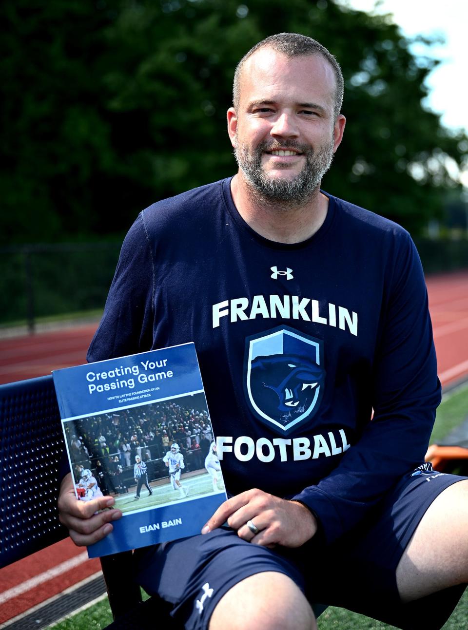 Franklin football coach Eian Bain with a copy of his book, "Creating Your Passing Game," Aug. 19, 2022.