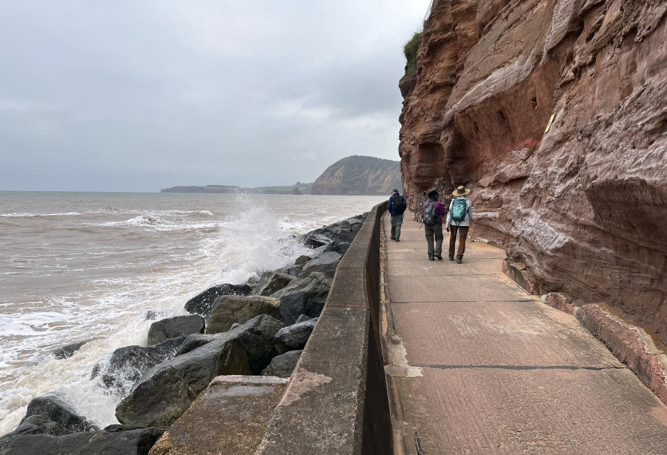 People walk between the beach and cliffs leaving Sidmouth, along the South West Coast Path, in southern England on April 26, 2023. (Steve Wartenberg via AP)