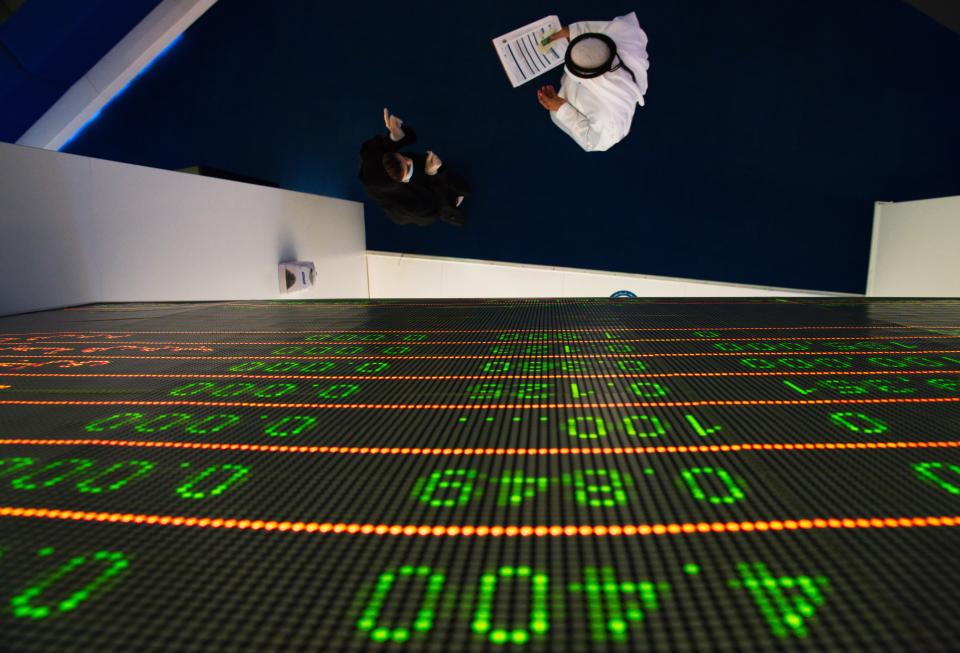 Two Emiratis talk on the floor of the Dubai Financial Market in Dubai, United Arab Emirates, Tuesday, July 7, 2020. Dubai reopened its Dubai Financial Market stock exchange Tuesday after closing its floor due to the coronavirus pandemic. (AP Photo/Jon Gambrell)