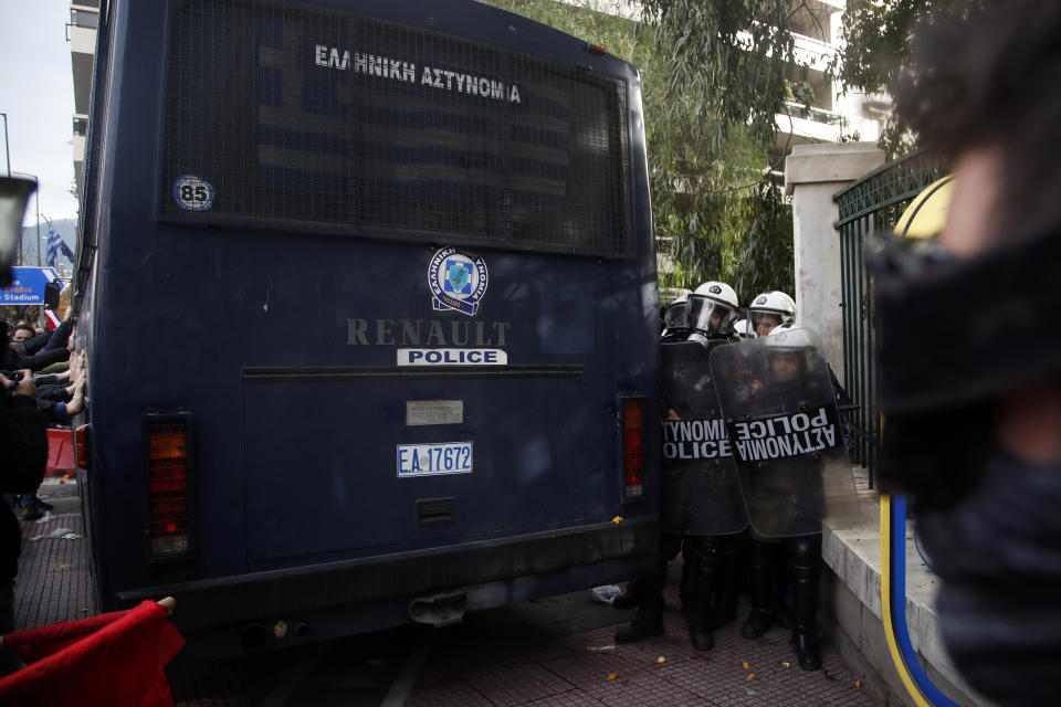 Riot police take cover as teachers and other protesters push police buses during clashes near the Prime Minister's office in Athens, Friday, Jan. 11, 2019. About 1,500 people took part in the protest. Teachers' unions oppose the government's selection process for the planned hiring of 15,000 new teachers over the next three years. (AP Photo/Thanassis Stavrakis)