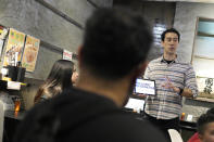 Frank Striegl, right, a guide of Tokyo Ramen Tours, explains foreign participants of a ramen tasting tour at Shinbusakiya, a ramen shop which offers "Hokkaido classics," at Shibuya district on April 2, 2024, in Tokyo. (AP Photo/Eugene Hoshiko)