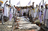 Farmers shout slogans as they block a railway track protesting against the new farm bills, at Devi Dass Pura village, about 20 kilometers from Amritsar, India. Farmers across the state have threatened to stop train services as they demanded a rollback in three new farm bills of the central government, stating that these are against the interests of farmers. (AP Photo/Prabhjot Gill)