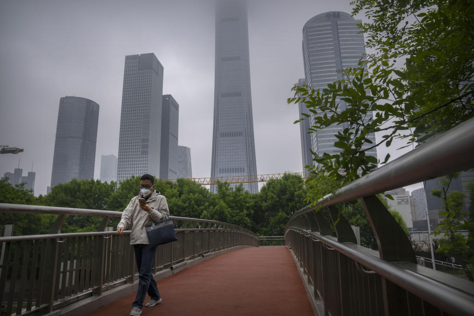 A man wearing a face mask walks across a pedestrian bridge in the central business district in Beijing during what is normally the morning rush hour, as most nonessential workers in the district have been ordered to work from home, Tuesday, May 10, 2022. China's capital began another round of three days of mass testing for millions of its residents Tuesday in a bid to prevent an outbreak from growing to Shanghai proportions. (AP Photo/Mark Schiefelbein)