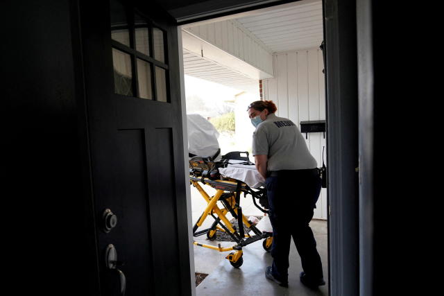 A paramedic moves a cot into the home of a COVID patient in Shawnee, Okla.