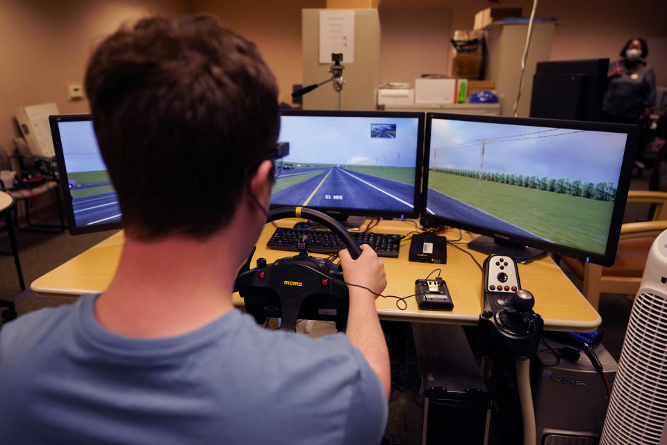 Tate Ellwood-Mielewski test drives on a simulator at the University of Michigan, Friday, April 29, 2022, in Ann Arbor, Mich. Michigan researchers plan to study how well those with autism spectrum disorder detect road hazards and assist the young motorists in sharpening their driving skills. The upcoming effort marks the second phase of a project that is funded by Ford Motor Co. and teams the Ann Arbor university with a local driving school. (AP Photo/Carlos Osorio)