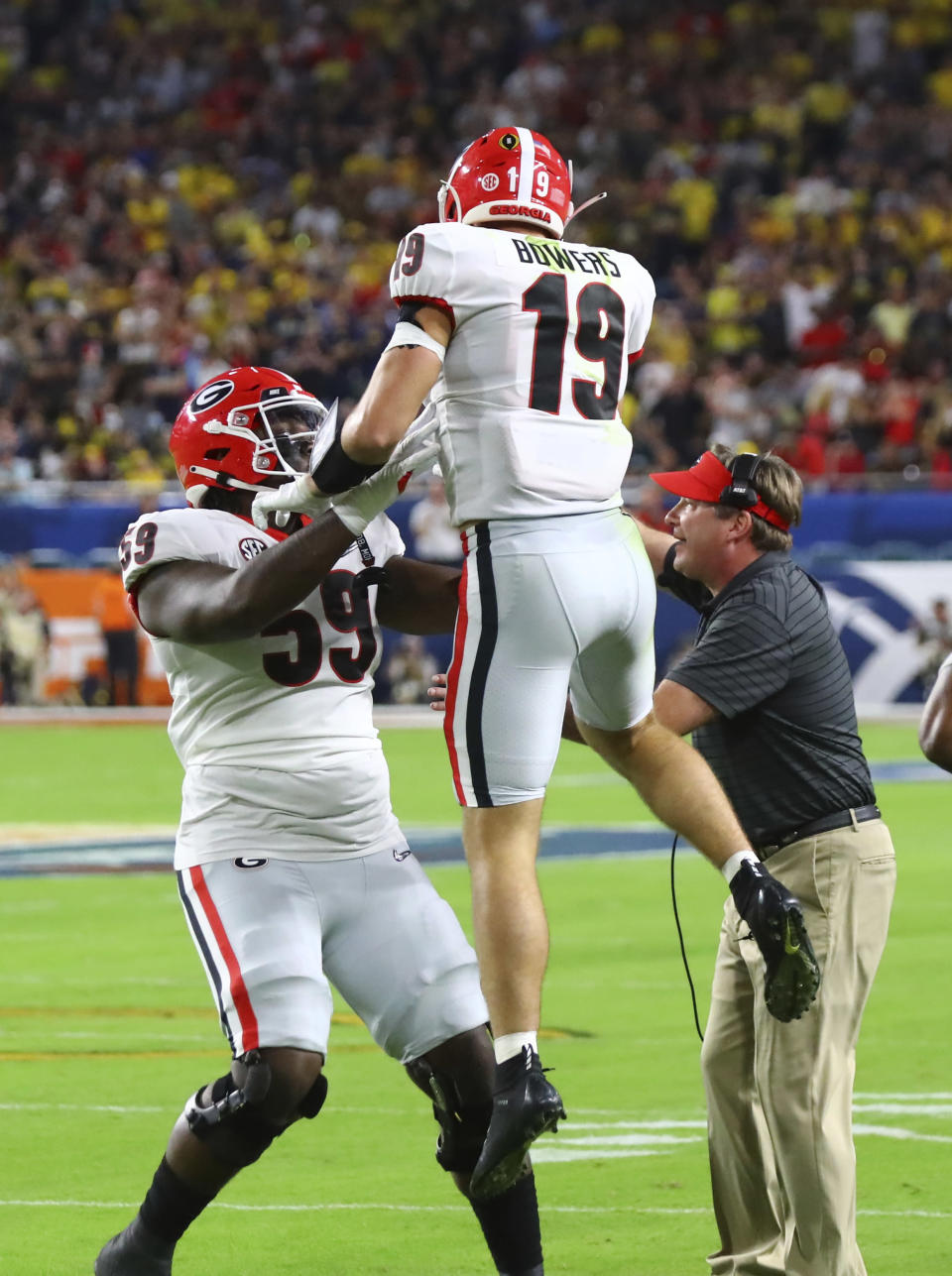 Georgia Bulldogs head coach Kirby Smart is on the field as Georgia Bulldogs offensive lineman Broderick Jones (59) celebrates their first touchdown by Georgia Bulldogs tight end Brock Bowers (19) at the 2021 College Football Playoff Semifinal between the Georgia Bulldogs and the Michigan Wolverines at the Orange Bowl at Hard Rock Stadium in Miami Gardens. (Curtis Compton/Atlanta Journal-Constitution via AP)