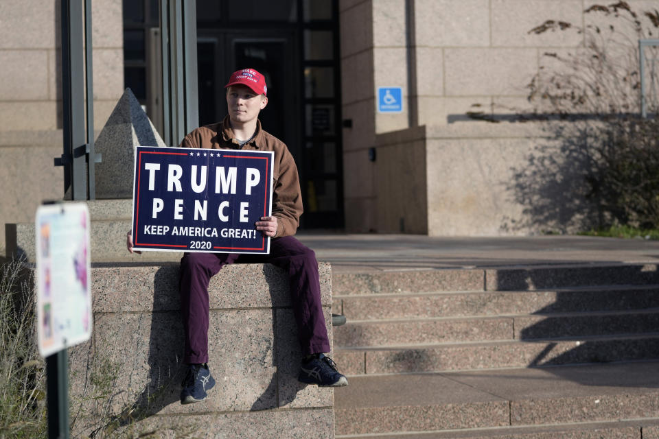 Jesse Smith sits with a Trump Pence sign outside the Minnesota Judicial Center, Thursday, Nov. 2, 2023, in St. Paul, Minn. Efforts to use the Constitution's "insurrection" clause to prevent former President Donald Trump from running again for the White House turn to Minnesota on Thursday with oral arguments before the state Supreme Court, a hearing that will unfold as a similar case plays out in Colorado. (AP Photo/Abbie Parr)