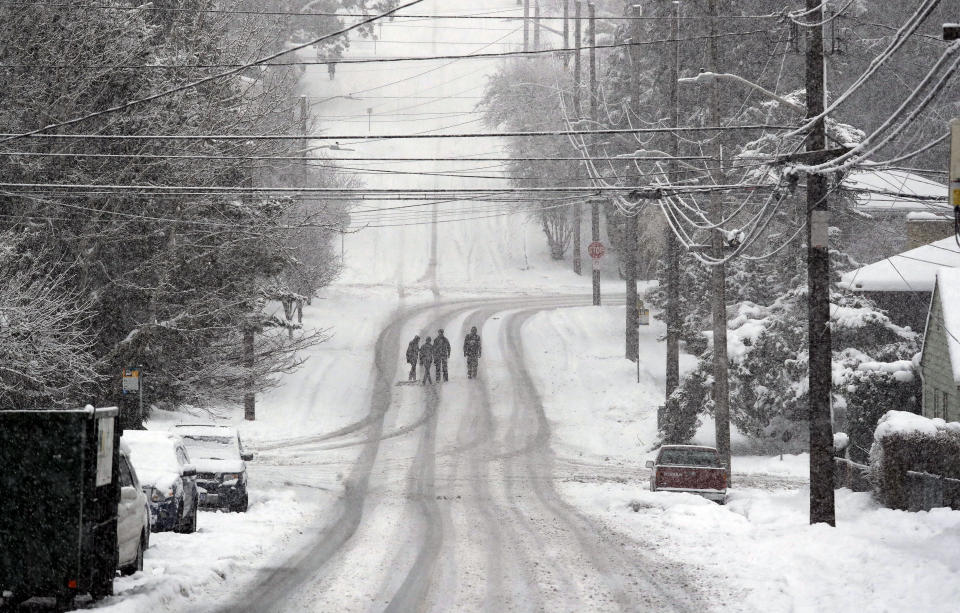 Pedestrians cross a deserted street as heavy snow falls Monday, Feb. 11, 2019, in Seattle. Schools closed across Washington state and the Legislature canceled all hearings Monday with winter snowstorms pummeling the Northwest again as a larger weather system wreaked havoc in the region and even brought snow to Hawaii. (AP Photo/Elaine Thompson)