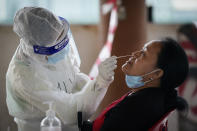 A medical worker collects a swab sample from a woman during coronavirus testing at a center for a private COVID-19 testing in Petaling Jaya, Malaysia, on Monday, Feb. 1, 2021. Malaysian authorities imposed tighter restrictions on movement to try to halt the spread of the coronavirus. (AP Photo/Vincent Thian)