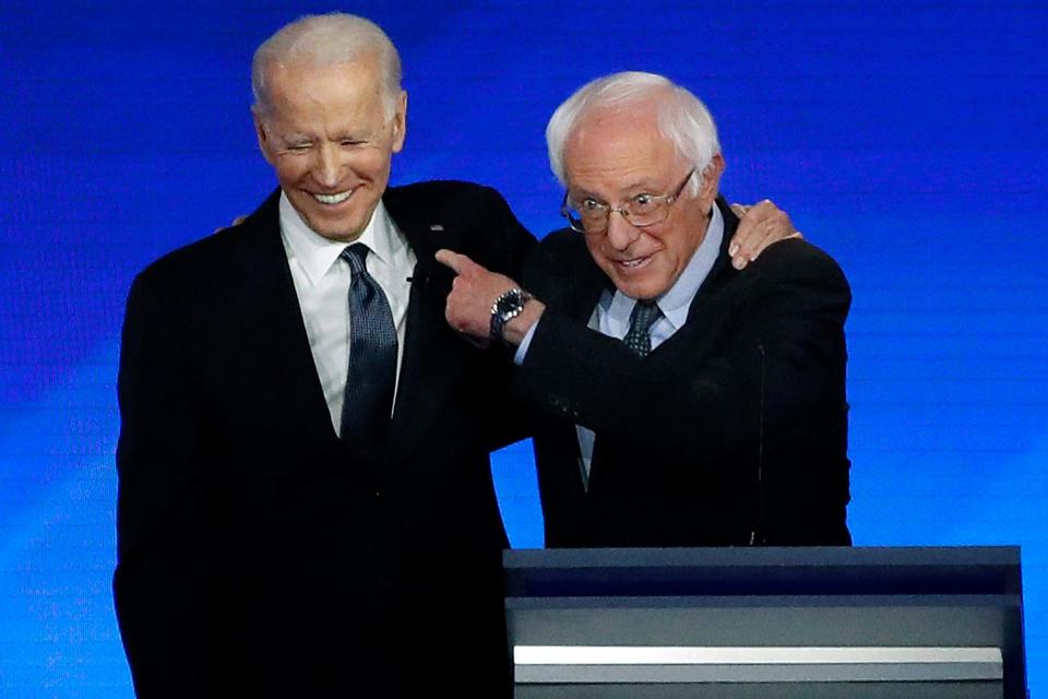 Former Vice President Joe Biden, left, embraces Sen. Bernie Sanders during a Democratic presidential primary debate on Feb. 7, 2020, at Saint Anselm College in Manchester, N.H.