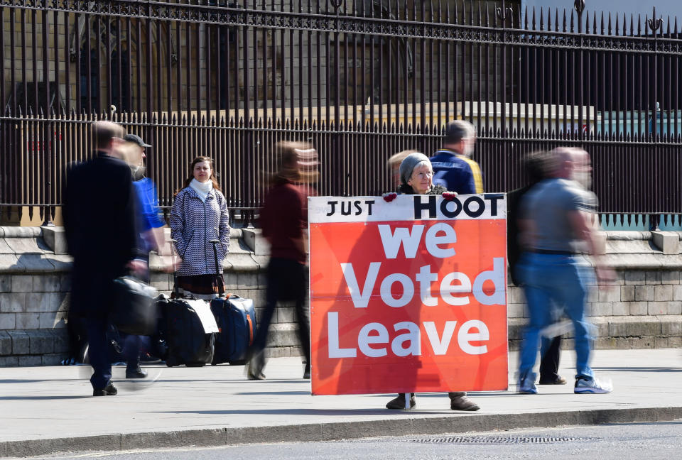 A supporter of Brexit holds a sign saying 'Just hoot, we voted leave' while others continue with their daily activities outside the Houses of Parliament, Westminster, London, ahead of the latest round of debates in the House of Commons concerning Brexit issues.